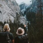 Foto Ivana Cajina - 2 mensen in een valei tussen bergen kijken naar de bergen