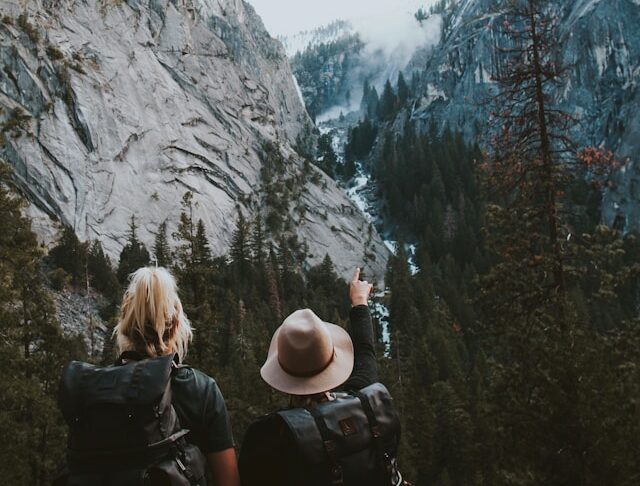 Foto Ivana Cajina - 2 mensen in een valei tussen bergen kijken naar de bergen